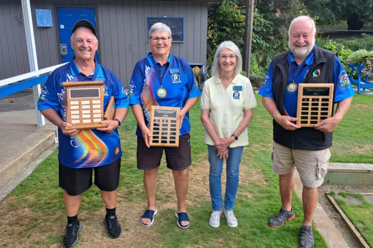 Four members holding up a total of 3 tournament plaques.