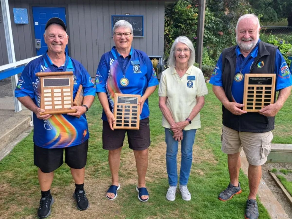 Four members holding up a total of 3 tournament plaques.